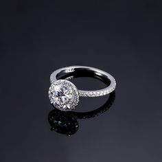 This sparkling halo setting features beautiful scalloped pavé gemstones that encircle the center gem and adorn the band. A gemstone-encrusted gallery makes this ring truly spectacular. Available in sizes 4 to 11.5, it's perfect for a heartfelt promise, commitment, wedding, or couples ring. Materials: 925 sterling silver, cubic zirconia Features: 2mm band, 7*7mm CZ stone Dazzling Halo Ring For Wedding, Dazzling Wedding Halo Ring, Diamond White Halo Ring With Round Band, Classic Halo Ring With Pave Setting For Gift, Classic Halo Ring With Pave Setting As Gift, Classic Round Cubic Zirconia Halo Ring, Moissanite Cluster Ring With Halo Design For Promise, Classic Halo Ring With Pave Setting, Dazzling Halo Diamond Promise Ring