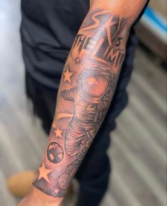 a man's arm with an astronaut tattoo on it and stars around the arm