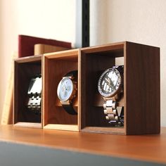 three watches are in a wooden box on a table