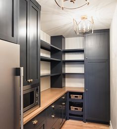 an empty kitchen with black cabinets and silver appliances in the corner, along with a chandelier hanging from the ceiling