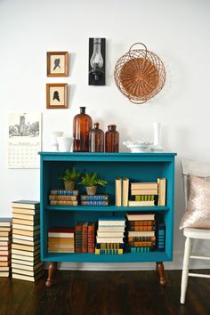 a blue book shelf with books and pictures on the wall