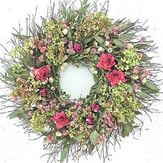 a wreath with pink flowers and greenery is shown in front of a white background