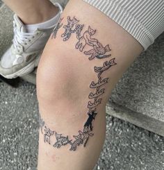 a woman's leg with tattoos on it and an arrow in the shape of cats