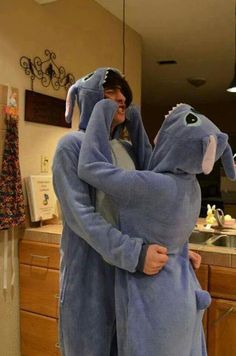 two people in pajamas hugging each other while standing next to a kitchen counter and sink