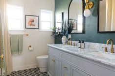 a bathroom with green walls and marble counter tops, gold faucets, black and white checkered floor