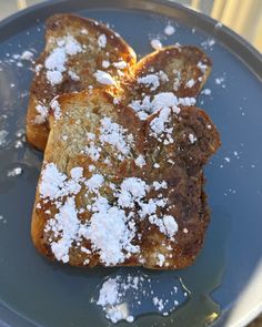 two pieces of french toast with powdered sugar on top sit on a plate, ready to be eaten