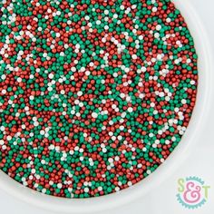 red, white and green sprinkles in a bowl on top of a table