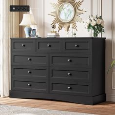 a black dresser in a room with flowers and a clock on the wall behind it