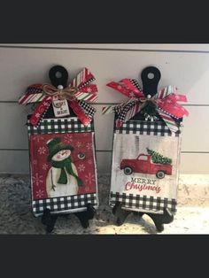 two christmas door hangers decorated with snowmen and plaid ribbon, one is holding a red truck