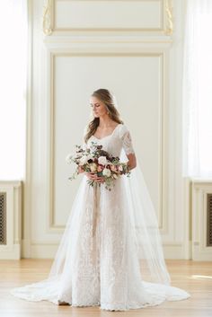 a woman in a white wedding dress holding a bouquet and standing on a hard wood floor