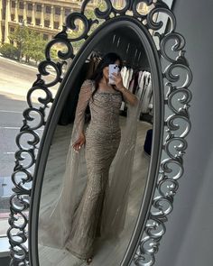 a woman taking a selfie in front of a mirror wearing a long sleeved dress