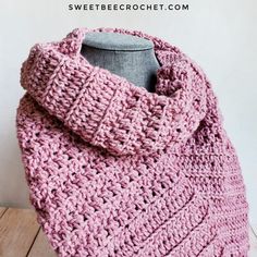 a pink crocheted cowl sitting on top of a wooden table