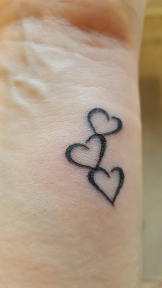 a small tattoo on the wrist of a woman with two hearts in the shape of a heart