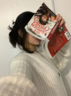 a woman is holding up a magazine to her face