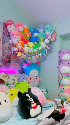 a room filled with lots of stuffed animals on top of a white bed covered in blankets