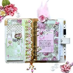 an open book with pink flowers and ribbons on the cover, surrounded by other items