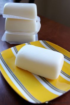 two pieces of soap sitting on top of a yellow and white plate next to a brown table