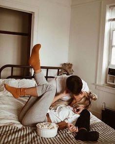 a woman laying on top of a bed next to a man with his feet up