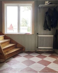 an empty room with some stairs leading up to the window and coat rack on the wall