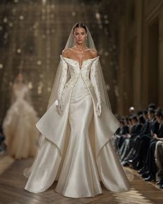 a model walks down the runway in an off - white wedding dress with long sleeves