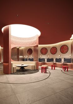 an empty room with red chairs and round tables in the center is lit by lights