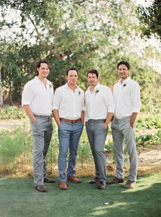 four men in white shirts and blue pants posing for a photo on the golf course