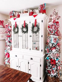 a white china cabinet decorated with christmas wreaths