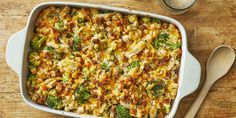 a casserole dish with broccoli, cheese and other toppings on a wooden table