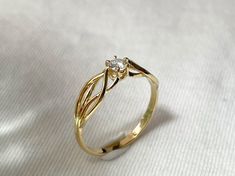 a yellow gold ring with a single diamond on the top, sitting on a white cloth