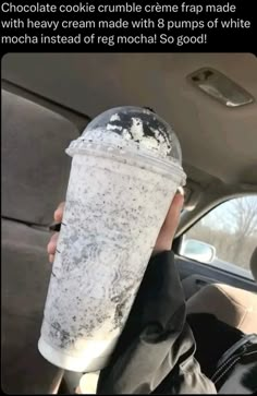 a person holding up a cup in the back seat of a car with ice cream on it