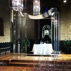 an empty stage set up for a wedding ceremony with clear chairs and white table cloth