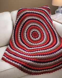 a white couch with a red and blue crocheted blanket on it