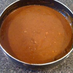 a metal pan filled with brown liquid on top of a granite countertop next to a knife