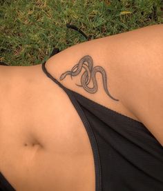 a woman with a tattoo on her stomach laying in the grass and wearing a black tank top