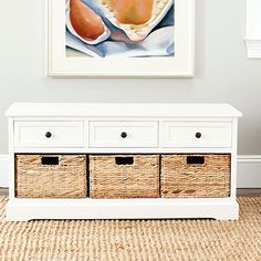 a white bench with baskets underneath it in front of a painting and rug on the floor