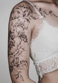 a woman with tattoos on her arms and shoulder is wearing a bra top that has flowers on it