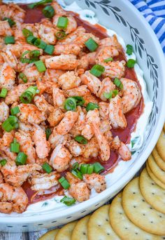 a white bowl filled with shrimp and sauce next to crackers