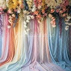 an arrangement of flowers and fabric draped in rainbow colors