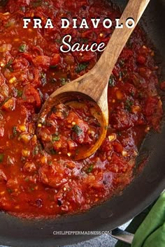 a wooden spoon in a pot filled with tomato sauce