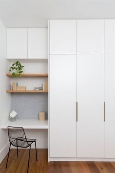 a white closet with shelves and a chair next to it on a hard wood floor