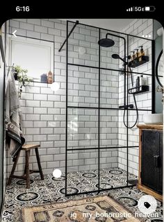 a bathroom with black and white tiles on the floor, shower head, and rug