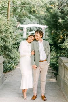 a man and woman standing next to each other on a path in the middle of trees