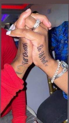 two people are holding hands with tattoos on their arms and the words love is all around them