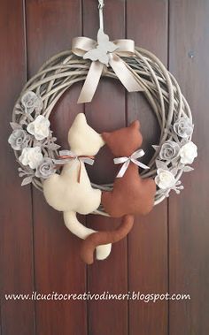 a wreath with two stuffed animals hanging from it's side on a wooden door