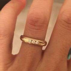 a woman's hand with a gold ring and three diamonds