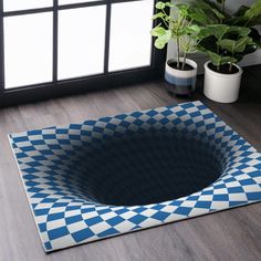 a blue and white checkered rug on the floor next to a potted plant