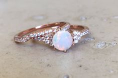 a white opal and diamond ring sitting on top of a table