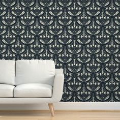 a white couch sitting in front of a black wallpapered with an intricate design