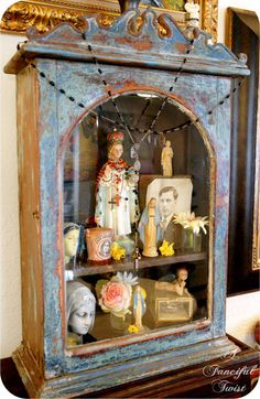 an old china cabinet with figurines and pictures on it