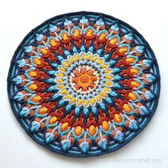 a crocheted circular design with orange, blue and yellow flowers on it's center